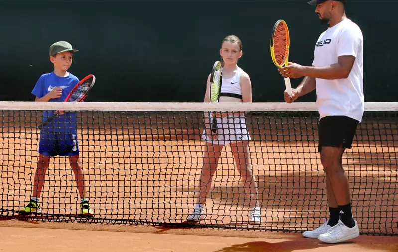Head Coach Hammad Siddiqui coaching two juniors at the net on a clay court